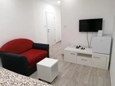 a living room with a red chair and a tv at Airport view Apartment in Belgrade