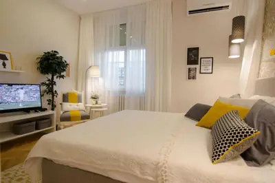 a bedroom with a white bed and a television at Studio Stil in Belgrade