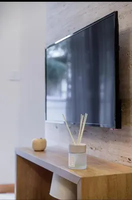 a flat screen tv on a wooden table with bamboo sticks at Belly3 in Belgrade