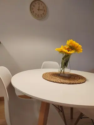 a vase of yellow flowers on a table with a clock at Yellow Gate in Novi Grad