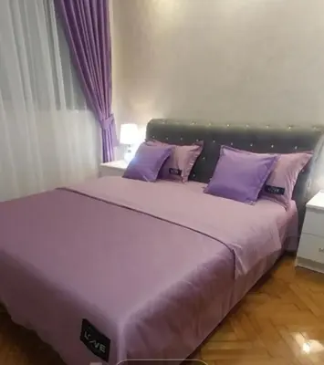 a large bed with purple pillows in a bedroom at Elena Lux in Belgrade