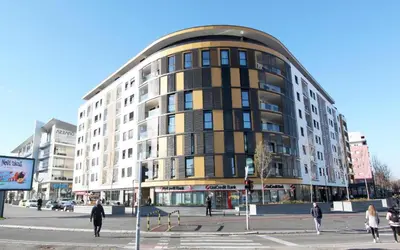 a building on a city street with people walking around it at Apartment SUN CITY 1 in Belgrade