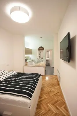 a bedroom with a black and white bed and a kitchen at Studio 10 in Belgrade
