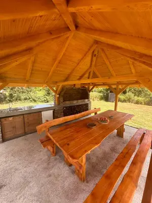 a wooden table sitting under a large wooden roof at Deda Momirov zavičaj in Tulež
