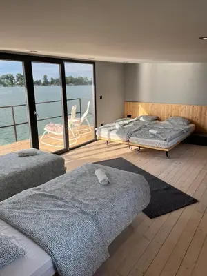two beds in a room with a view of the water at Splav Shoom in Ostružnica