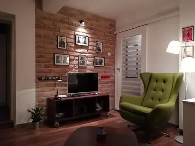 a living room with a green chair and a television at Gray apartment in Čukarica