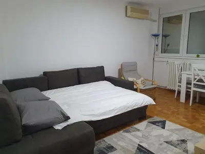a living room with a couch with a white blanket at AS Apartment in Tošin Bunar