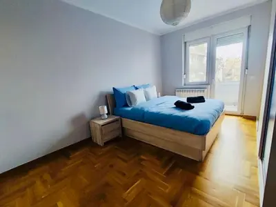 a bedroom with a blue bed and a wooden floor at Vracar hideaway with private garage in Belgrade